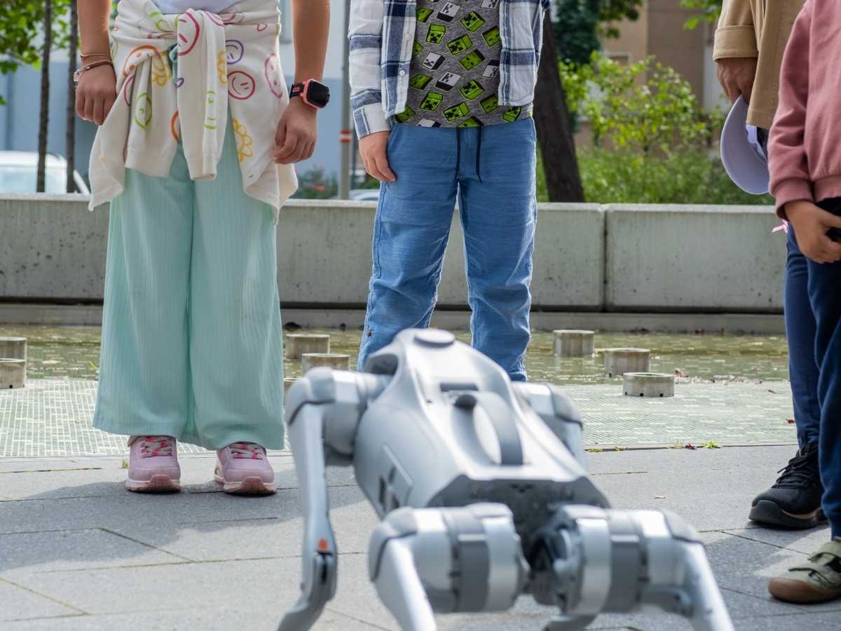 Kinder beobachten einen Roboterhund bei einer Technikaktivität im Freien