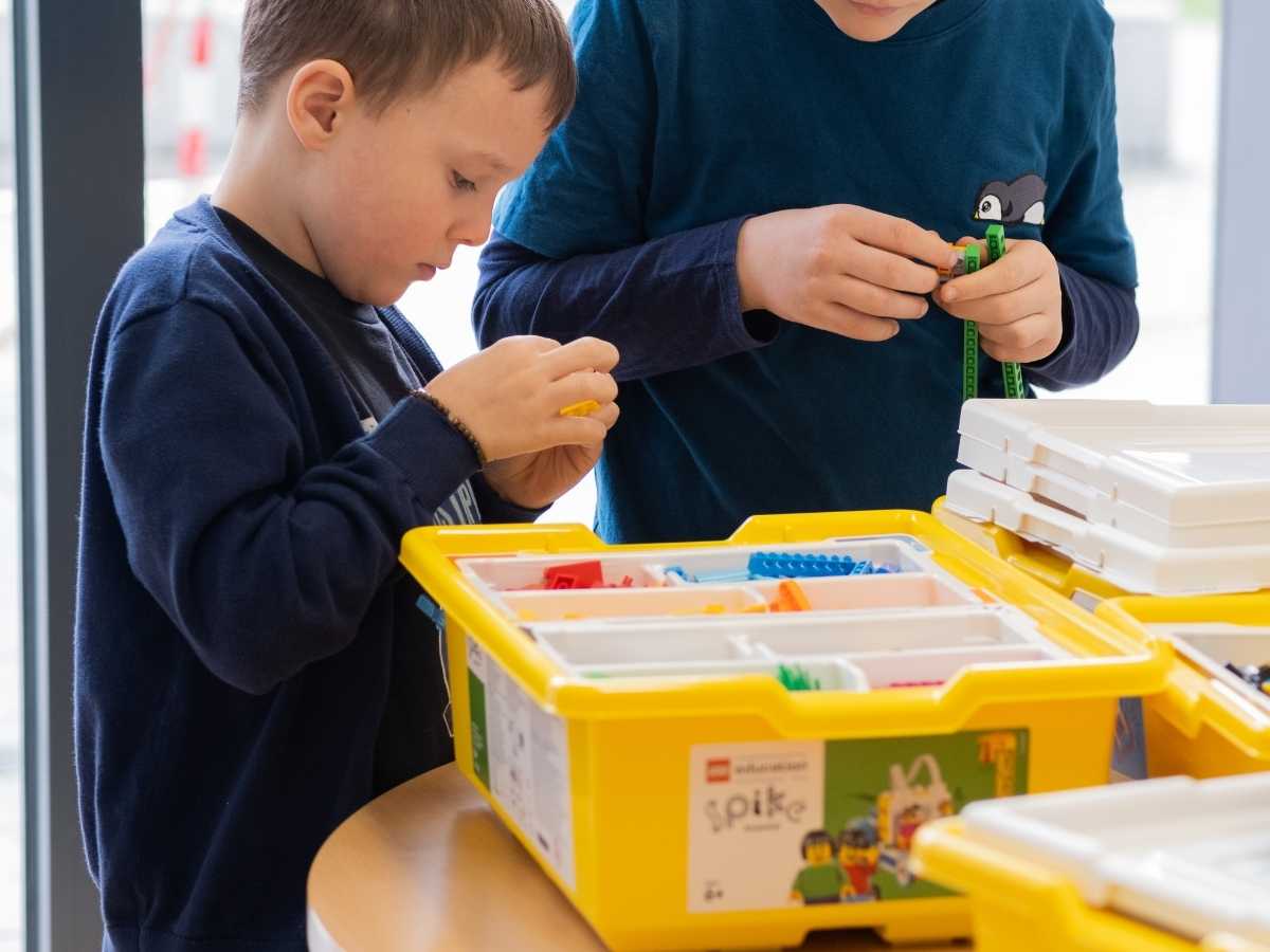 Kinder wählen LEGO SPIKE Teile für ein Robotikprojekt aus