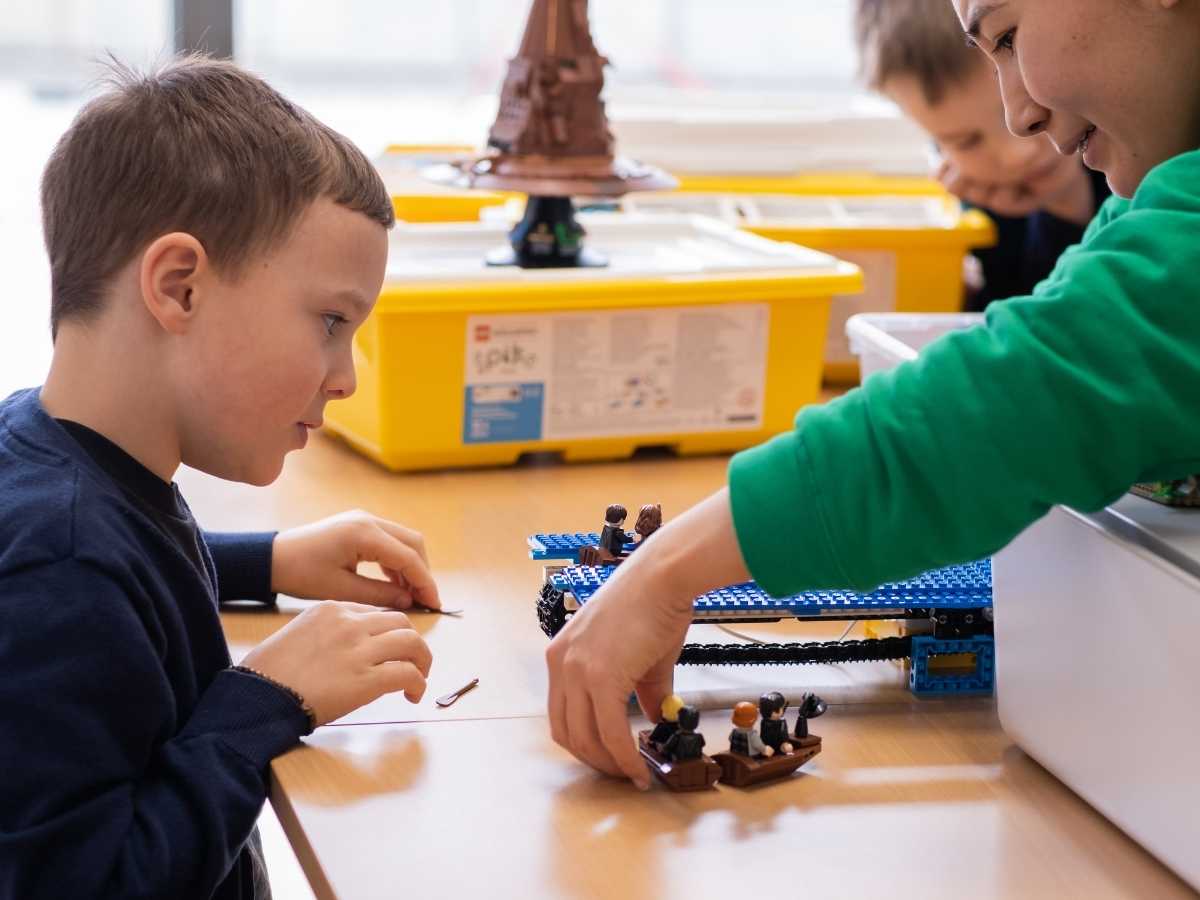 Kind arbeitet gemeinsam mit Trainerin an einem LEGO Modell im Robbo Club.