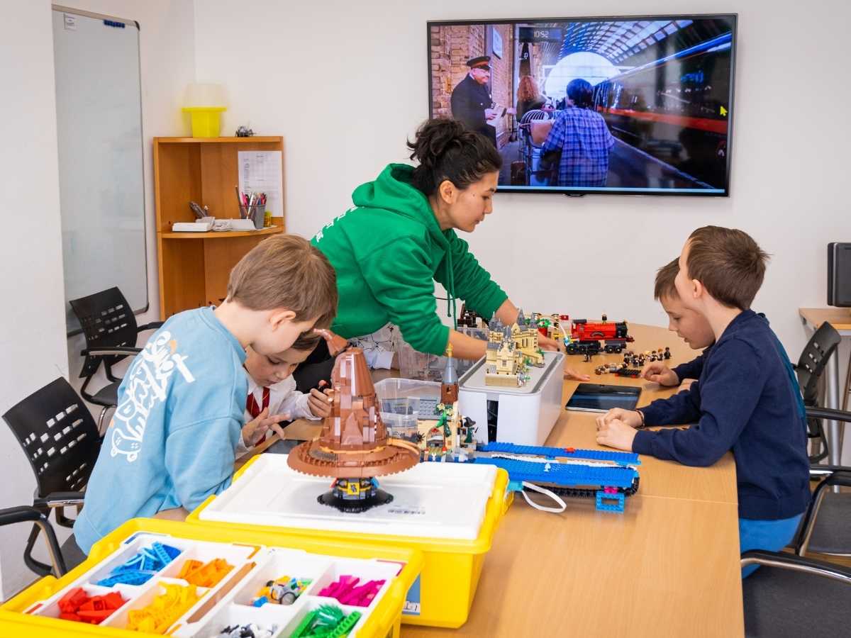 Kinder arbeiten gemeinsam an LEGO Projekten im Robbo Club Klassenraum.