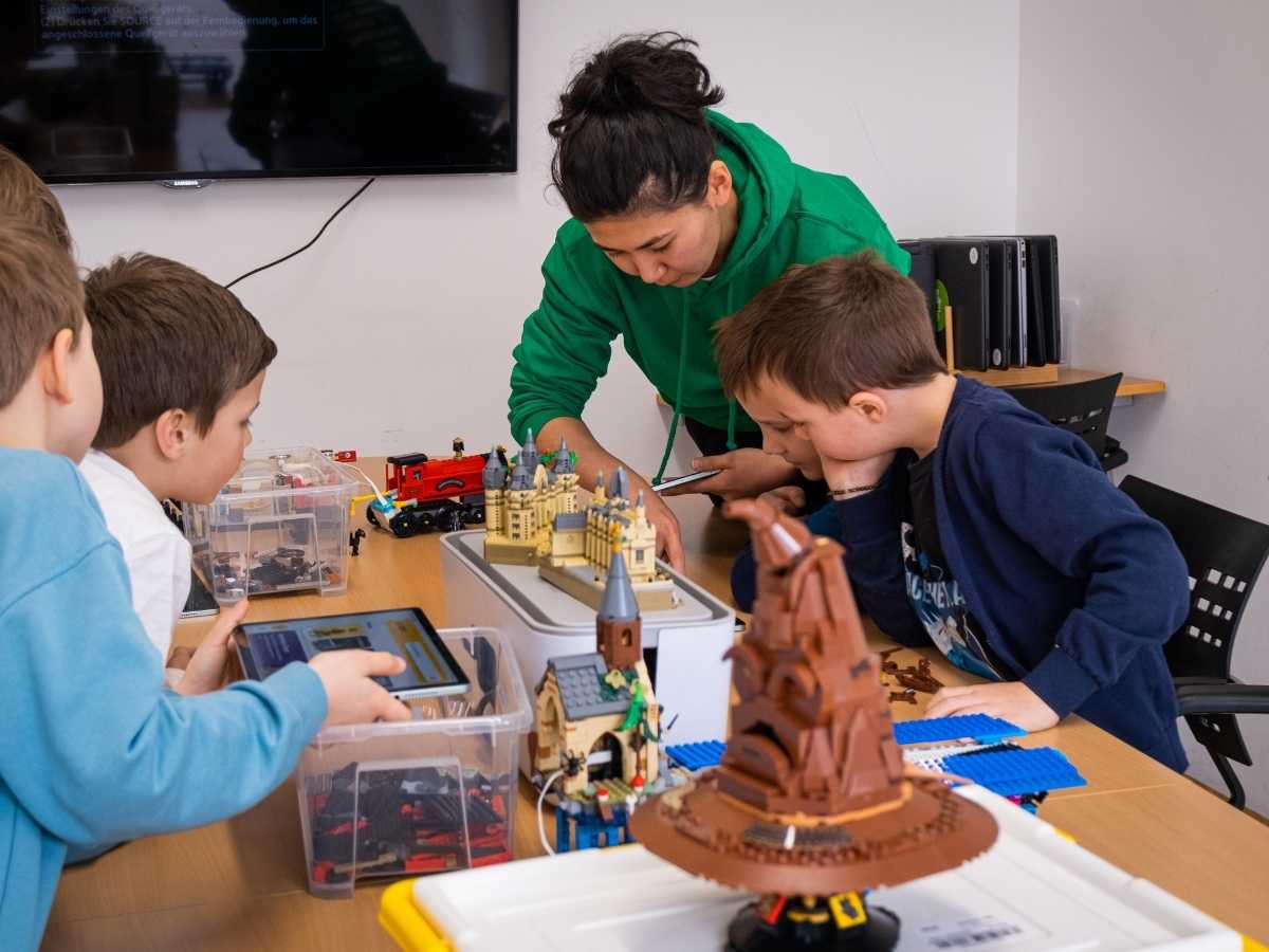 Kinder bauen gemeinsam mit Trainerin eine LEGO-Burg im Robbo Club