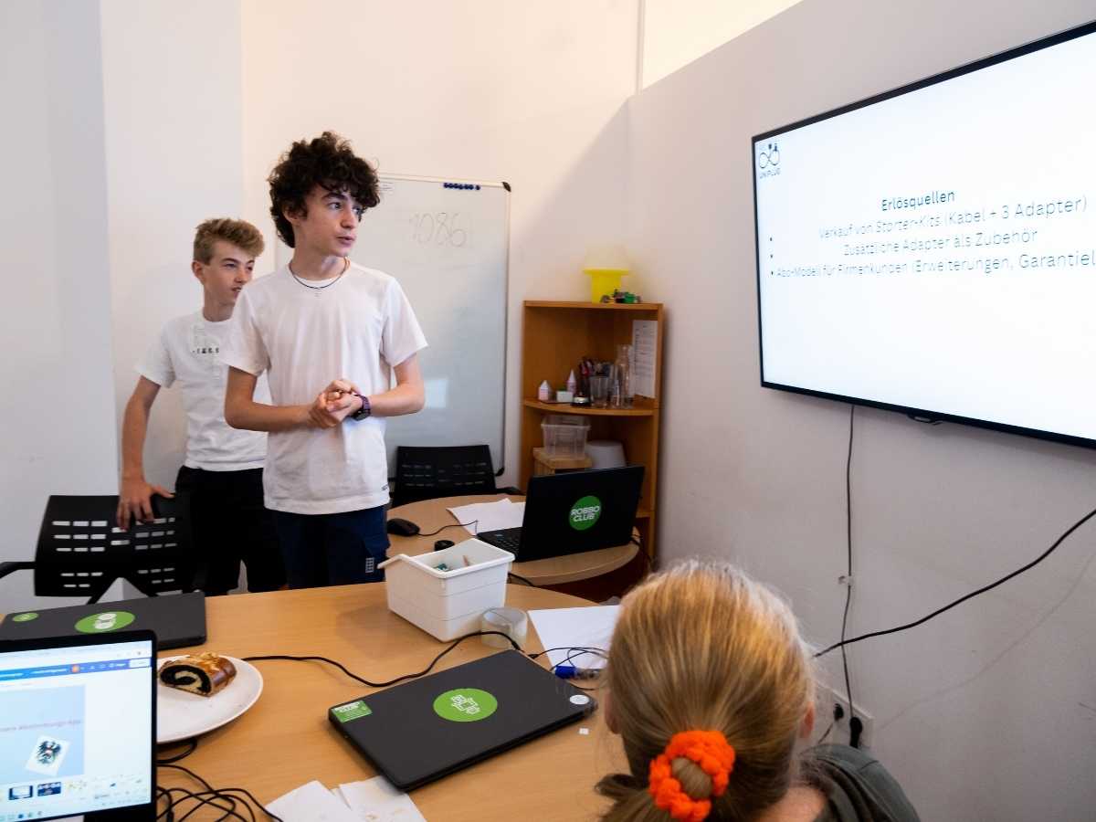Jugendliche präsentieren ein Projekt vor dem Bildschirm im Robbo Club