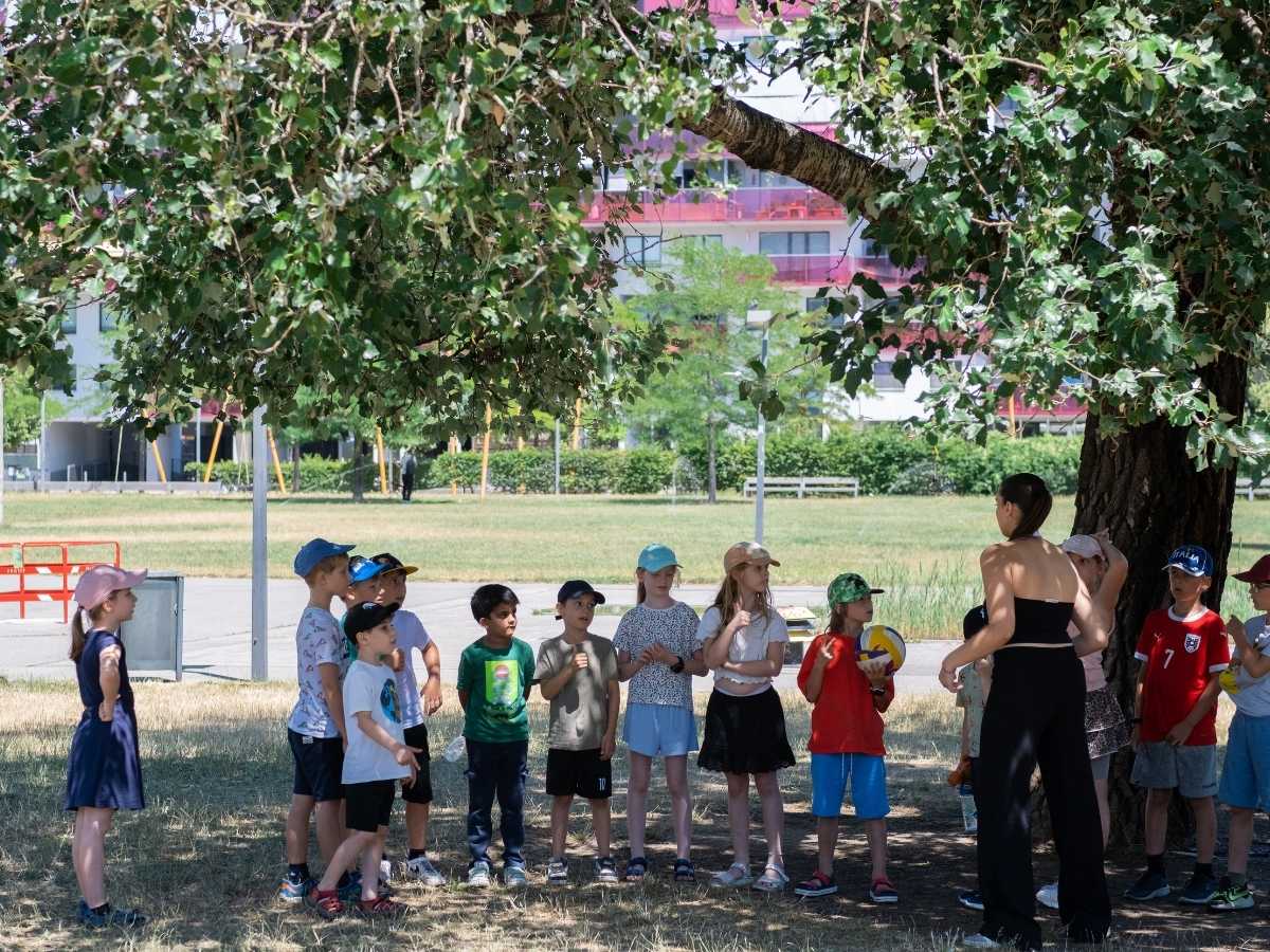 Kinder hören einer Trainerin bei einer Outdoor-Aktivität zu
