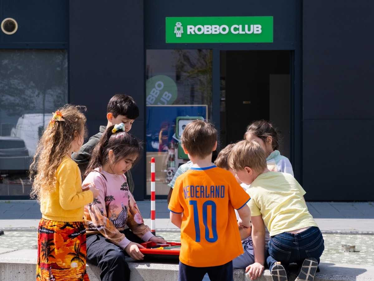 Kinder programmieren gemeinsam vor dem Eingang des Robbo Club.