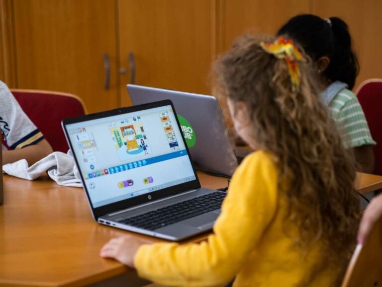 Mädchen programmiert im ROBBO Club am Laptop ein Spiel aus bunten Blöcken