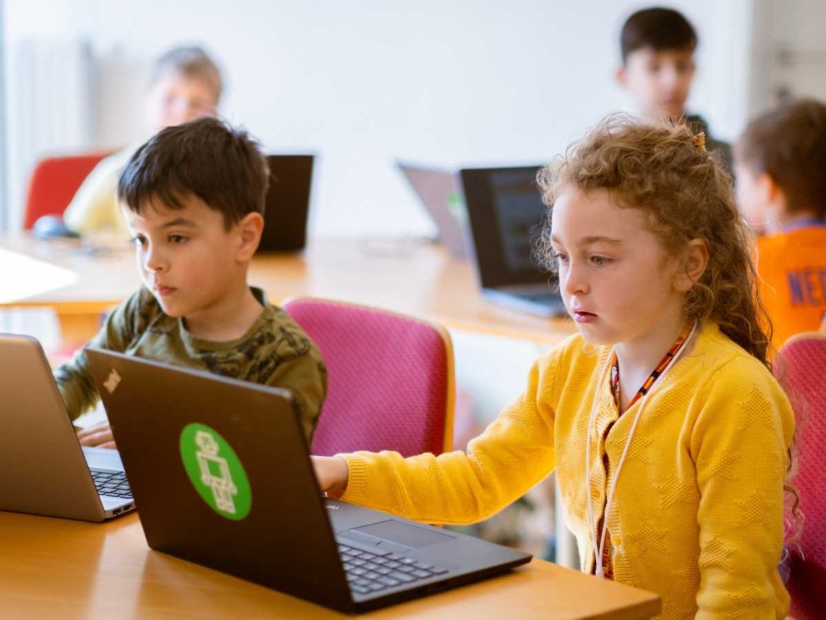 Kinder programmieren gemeinsam an Laptops im Robbo Club Unterricht