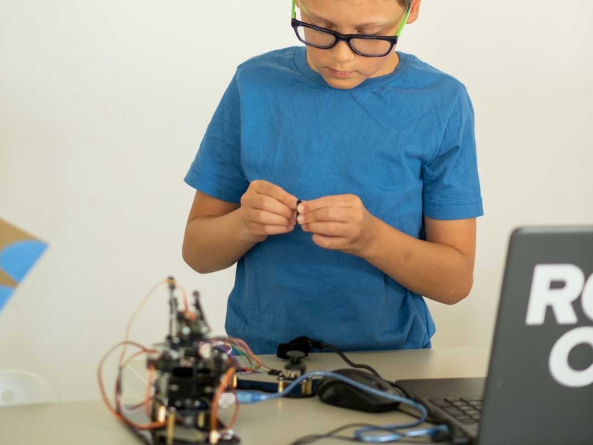 Kind montiert elektronische Bauteile während des Robotikunterrichts