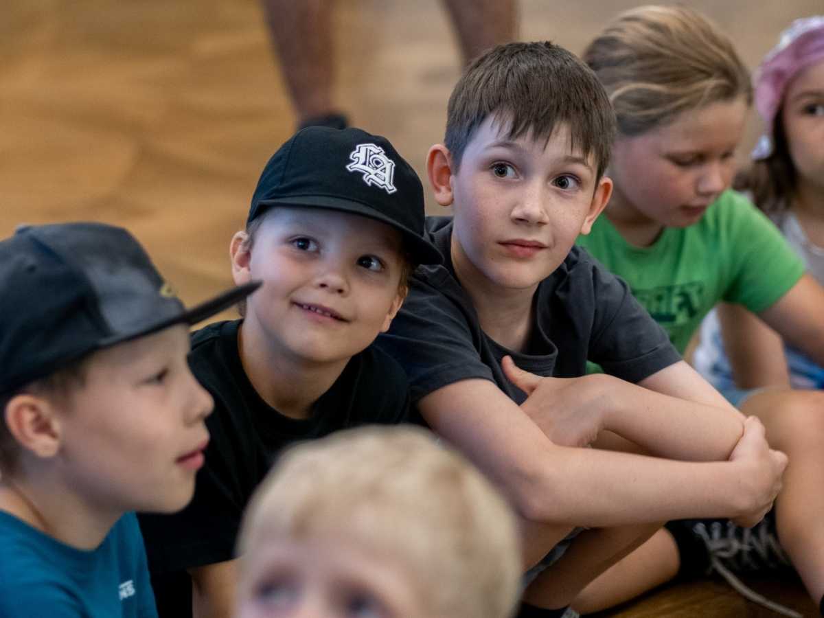 Kinder sitzen aufmerksam und hören einer Erklärung zu