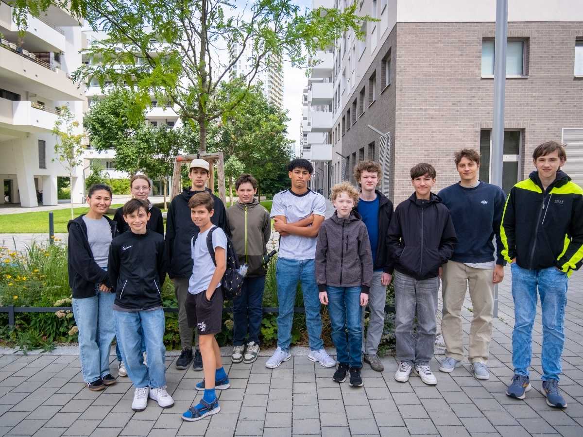 Gruppe von Jugendlichen und Trainern steht gemeinsam im Außenbereich eines Wohnquartiers