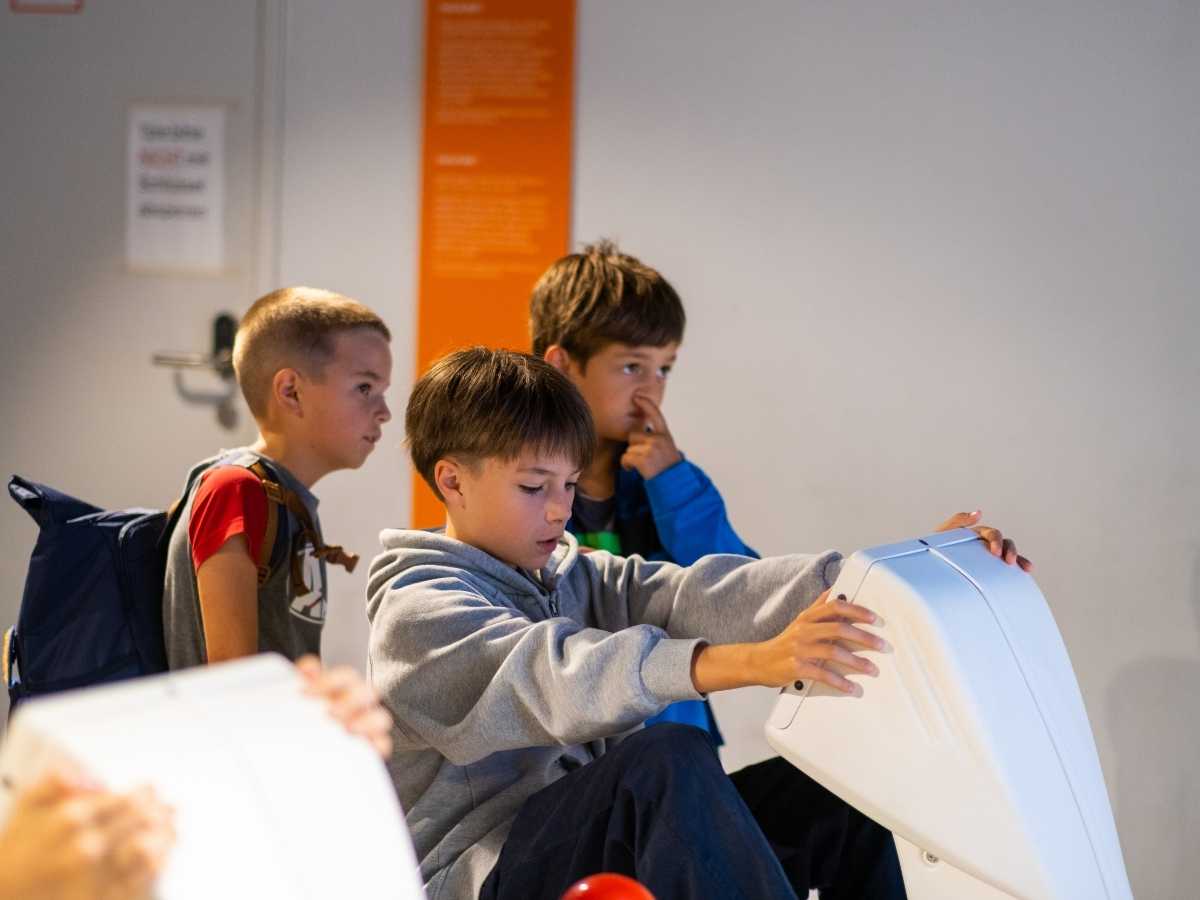 Kinder erkunden eine interaktive technische Installation im Innenraum