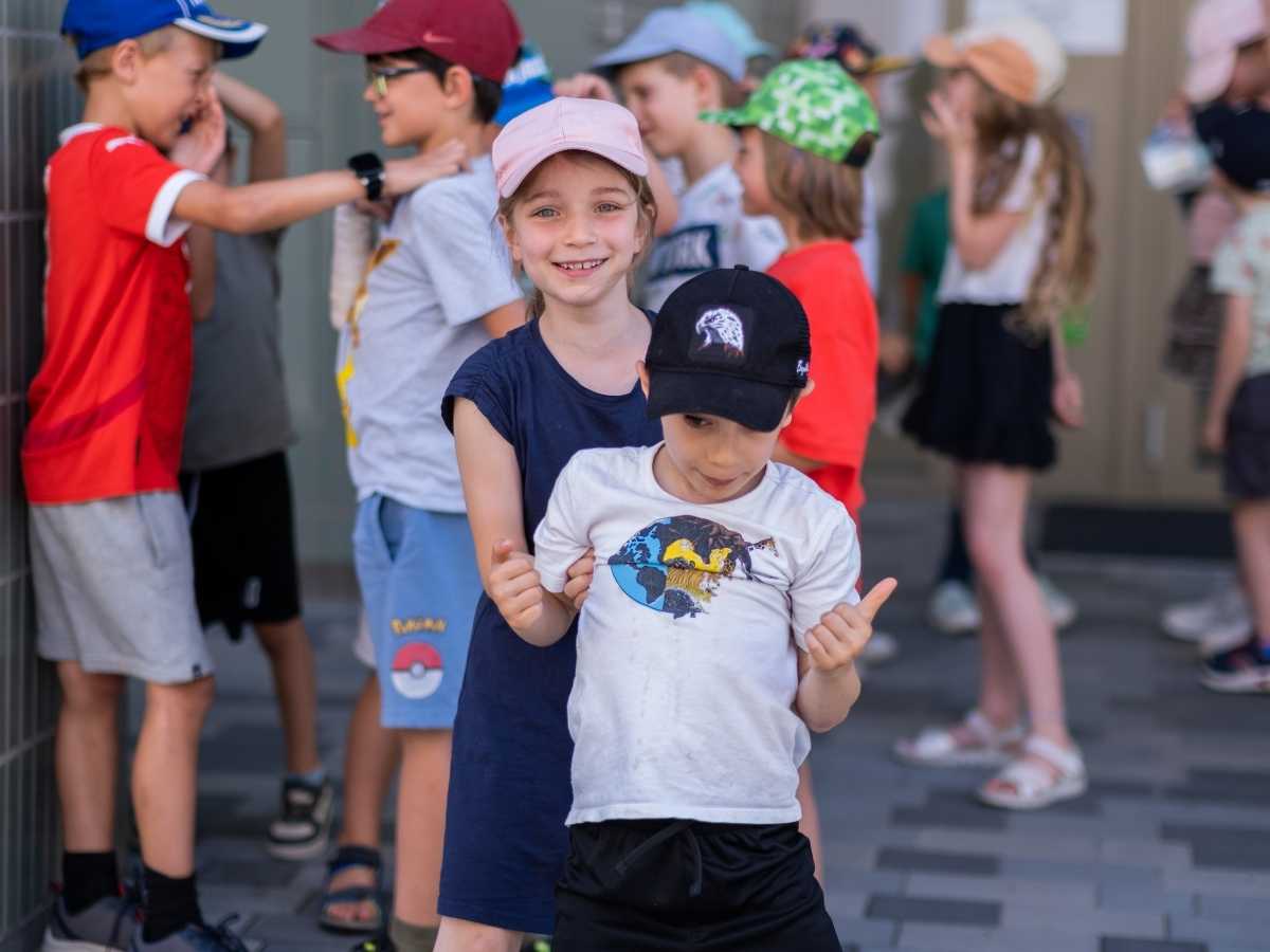 Zwei Kinder posieren fröhlich vor anderen Camp-Teilnehmern