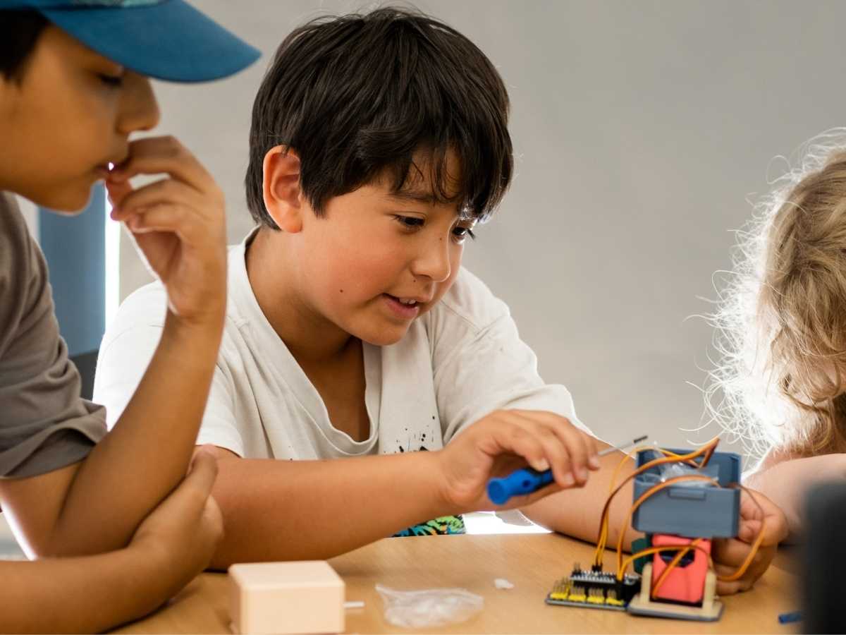 Kind schraubt elektronische Bauteile an einem selbstgebauten Roboter