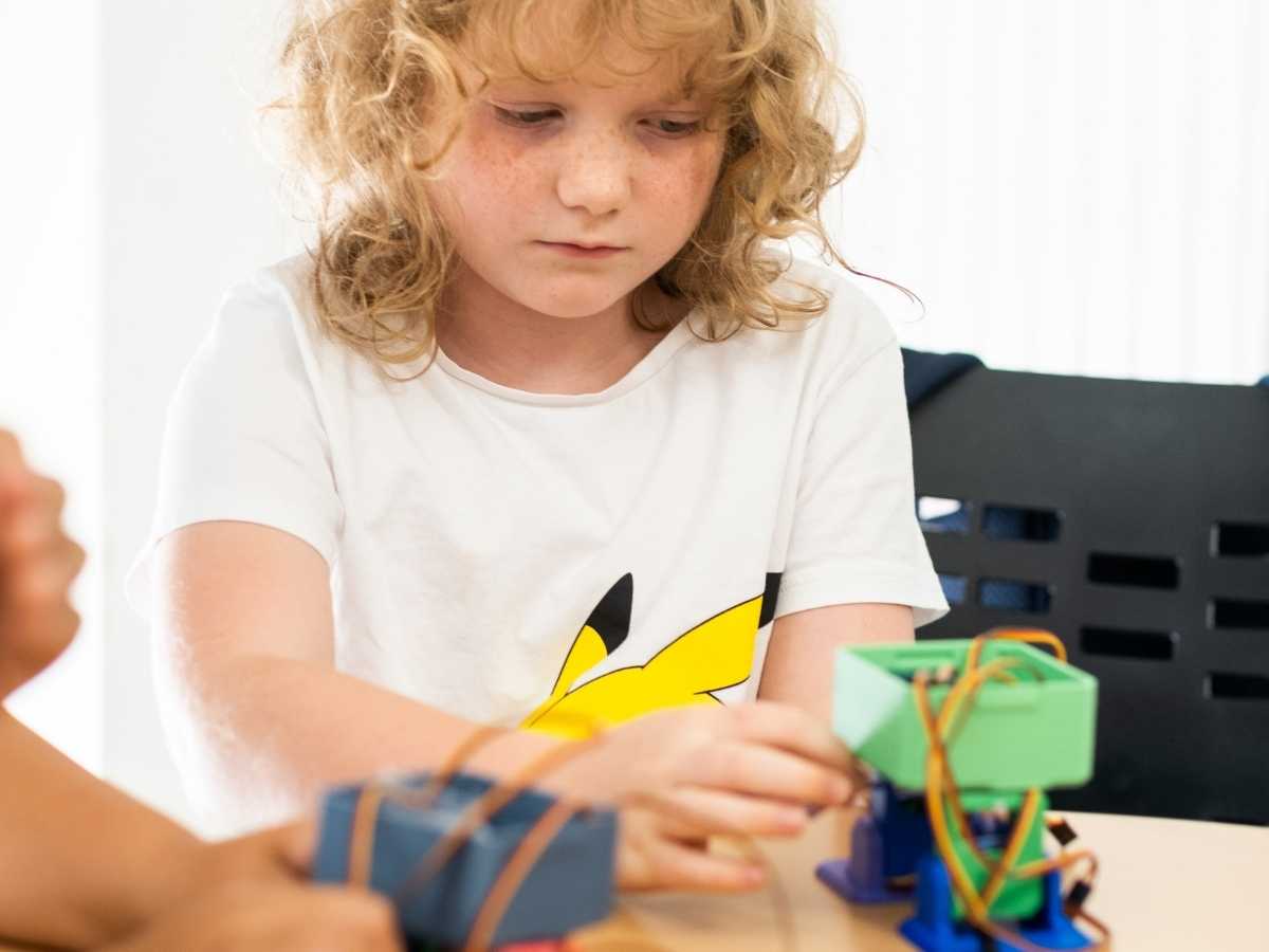 Kind testet einen selbstgebauten Roboter auf dem Tisch