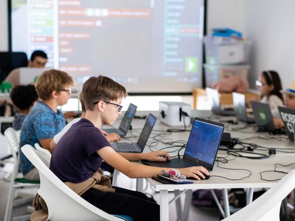 Kinder programmieren gemeinsam an Laptops im Robbo Club Kurs