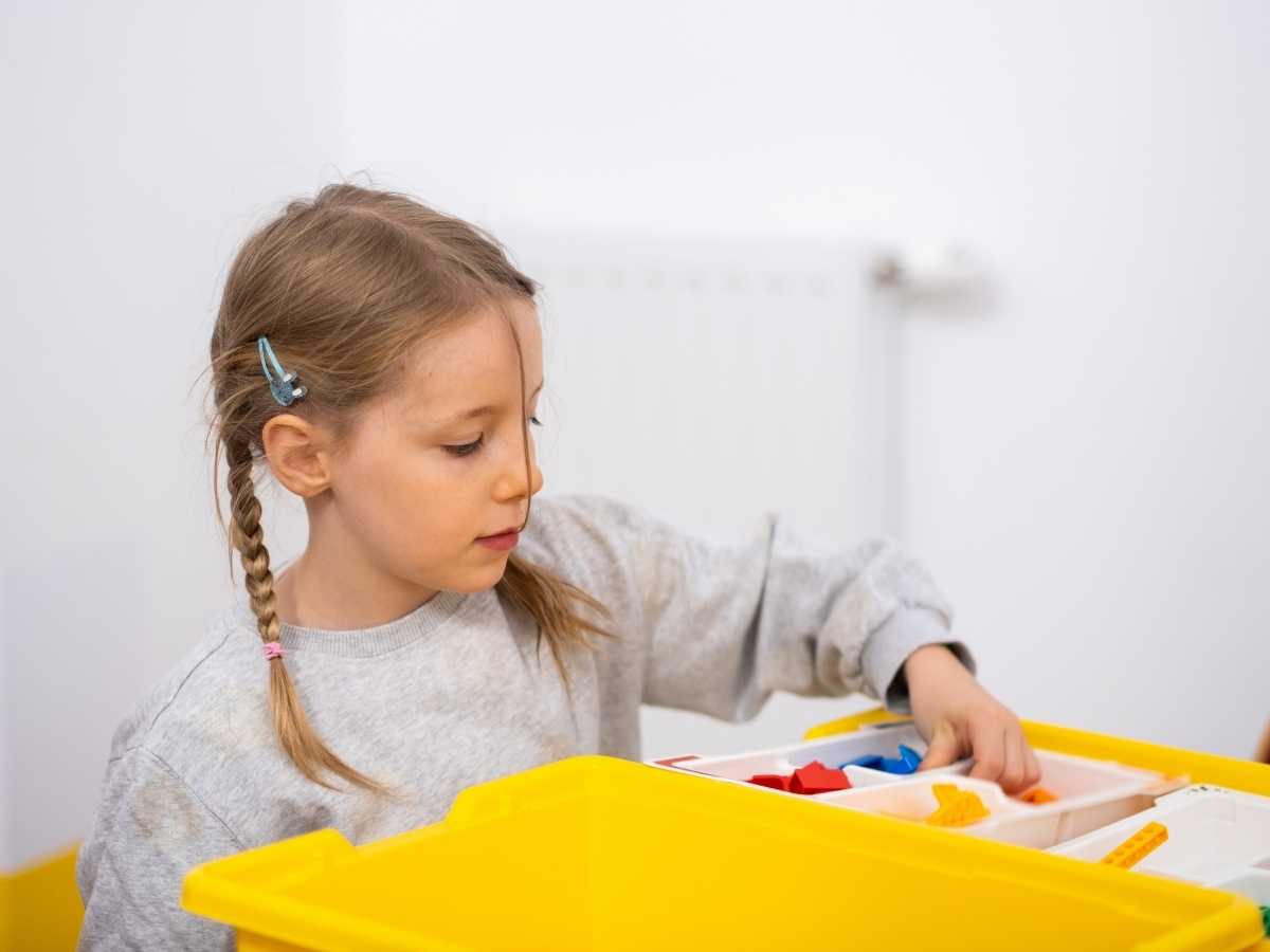 Kind sortiert LEGO Bausteine im Technik-Workshop des Sommer-Camps