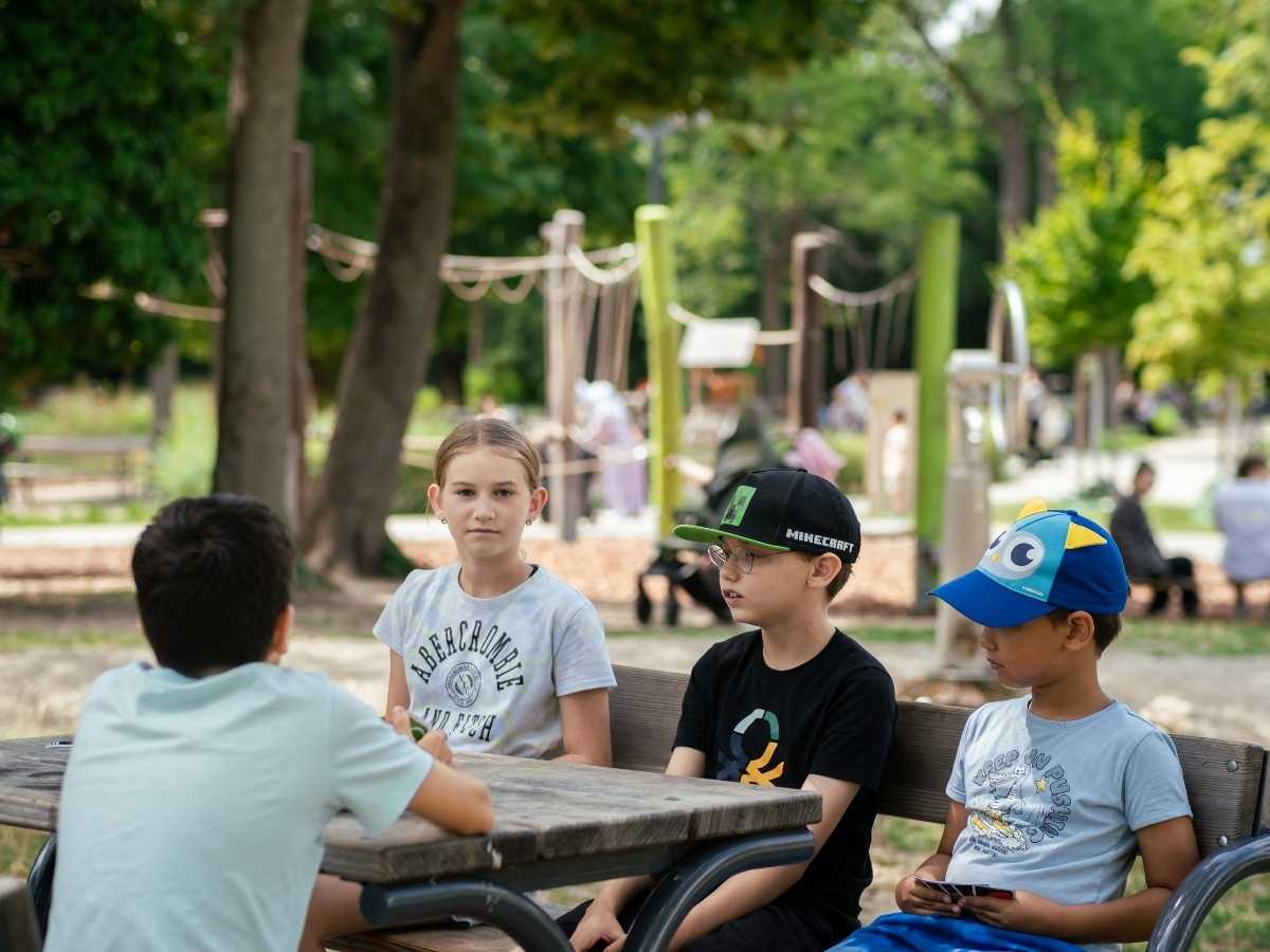 Kinder sitzen gemeinsam an einem Tisch und tauschen sich im Rahmen eines Robbo Club Programms aus