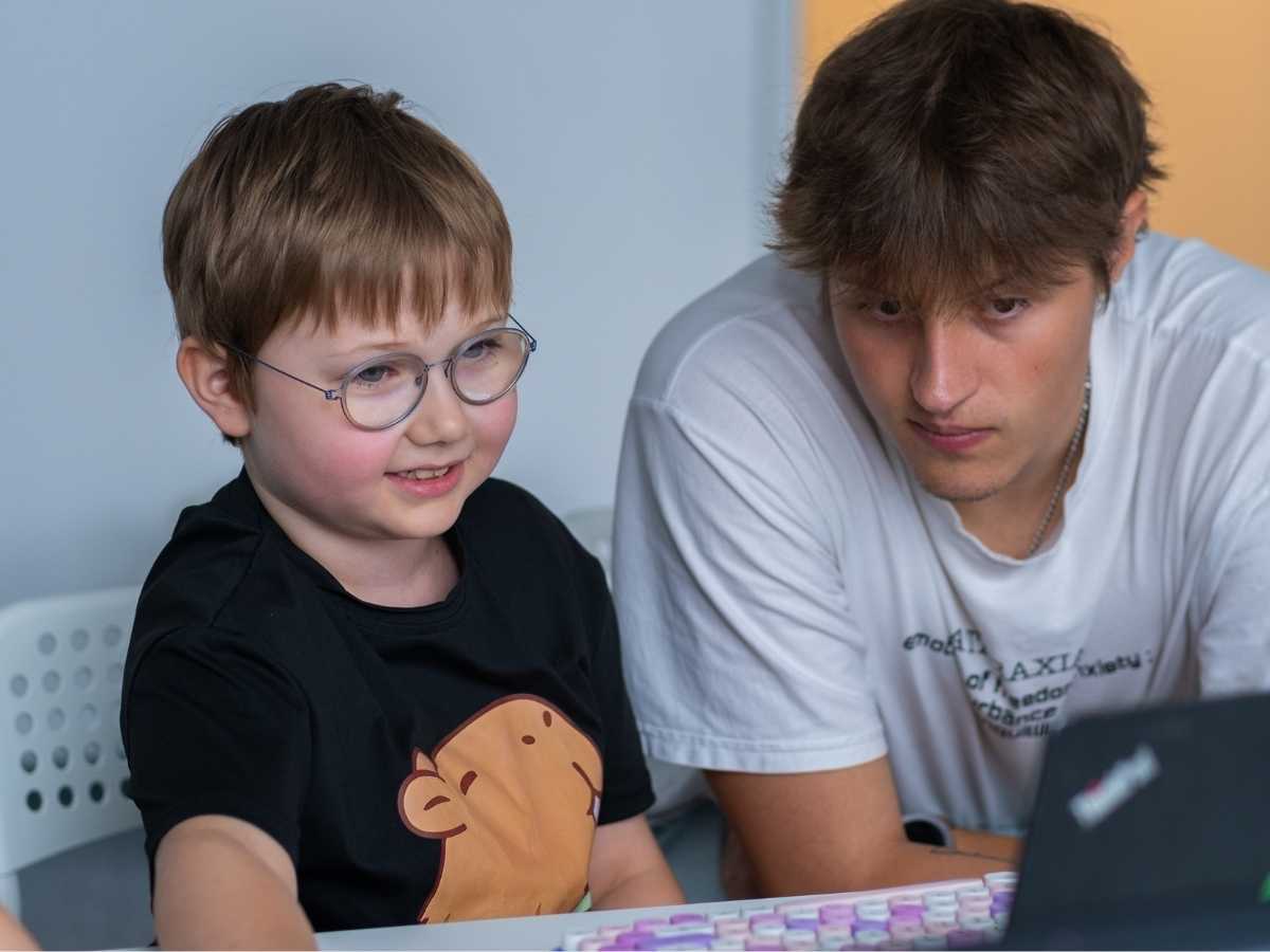 Kind arbeitet am Laptop gemeinsam mit einem Robbo Club Trainer