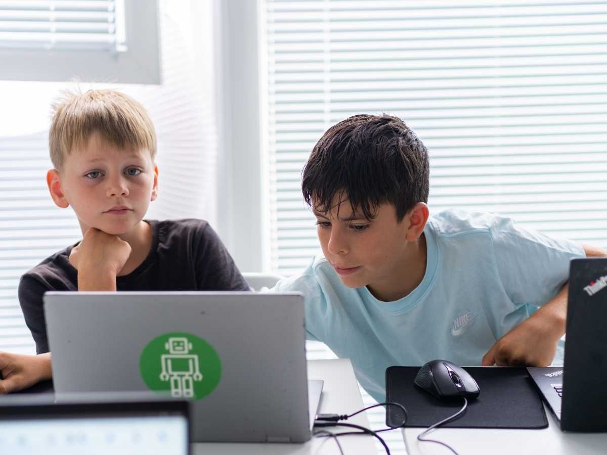 Zwei Kinder arbeiten gemeinsam an einem Laptop während eines Robbo Club Kurses