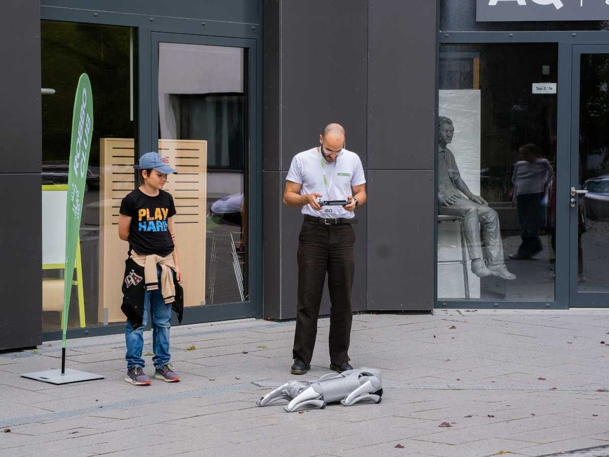 Kind steuert einen Roboter im Freien gemeinsam mit einem Trainer von Robbo Club