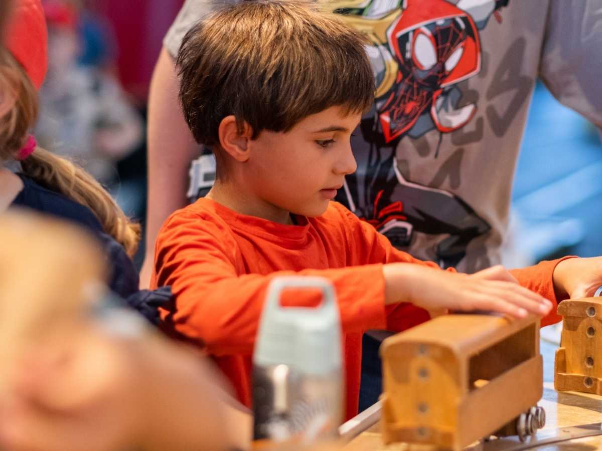 Kind arbeitet konzentriert an einem mechanischen Modell im Technik-Workshop