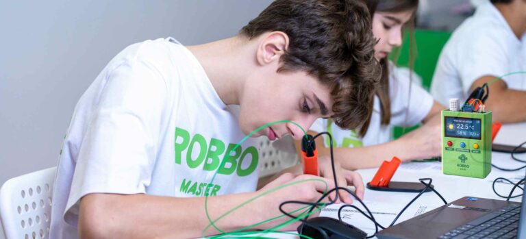 Kind arbeitet konzentriert an einem Wetter-Vorhersager mit Sensoren und Elektronik im ROBBO Club