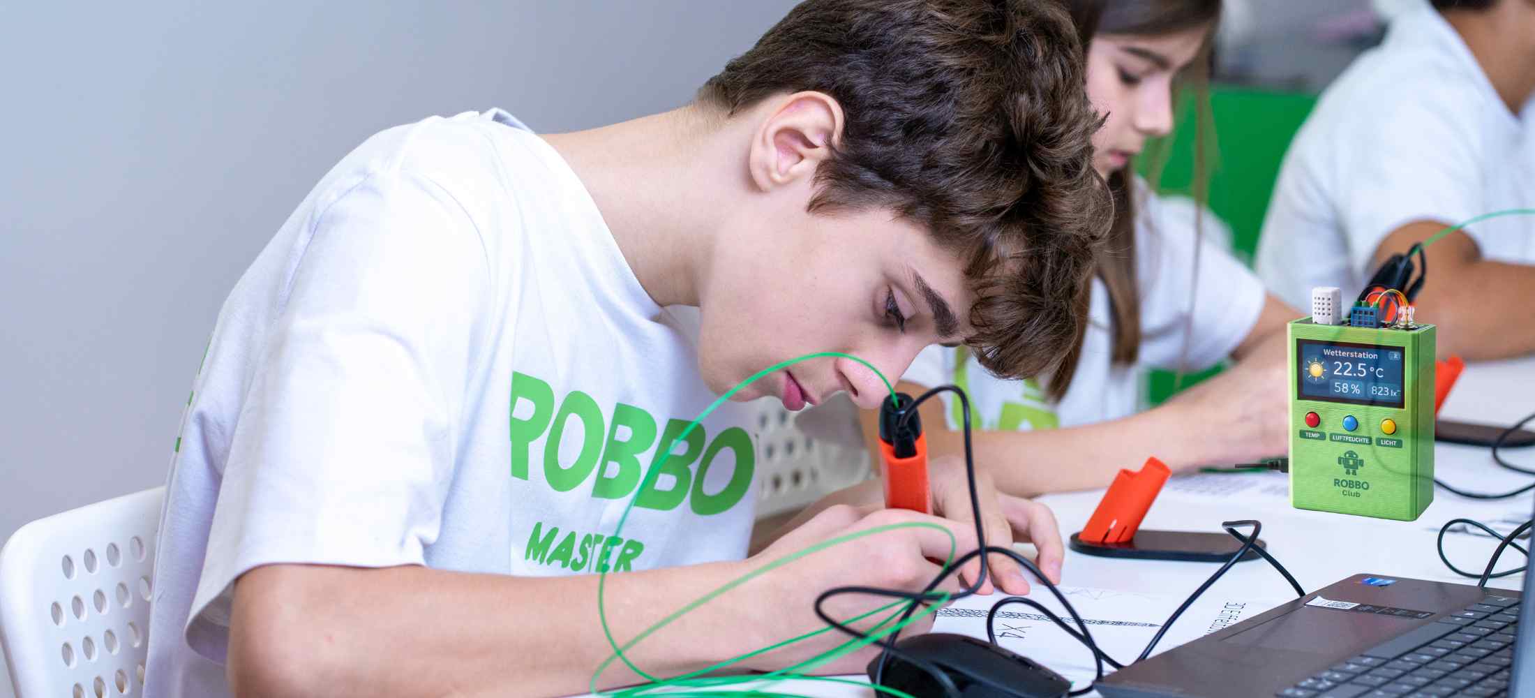 Kind arbeitet konzentriert an einem Wetter-Vorhersager mit Sensoren und Elektronik im ROBBO Club
