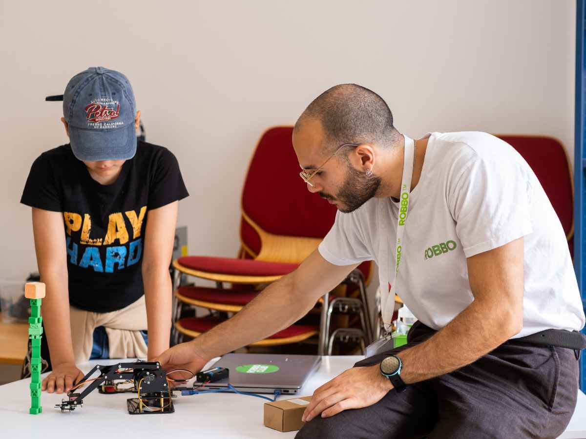 Kind und Trainer testen einen mechanischen Roboterarm