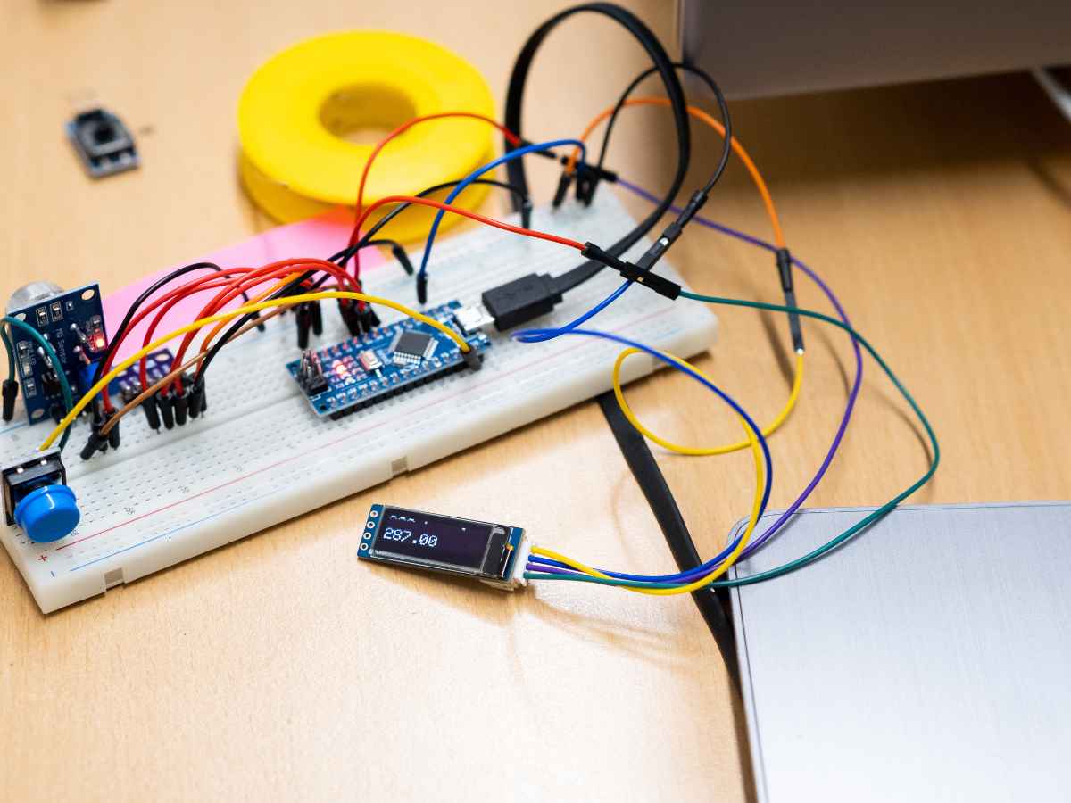 Elektronikprojekt mit Mikrocontroller, Sensoren und OLED-Display zur Anzeige von Wetterdaten auf einem Breadboard.