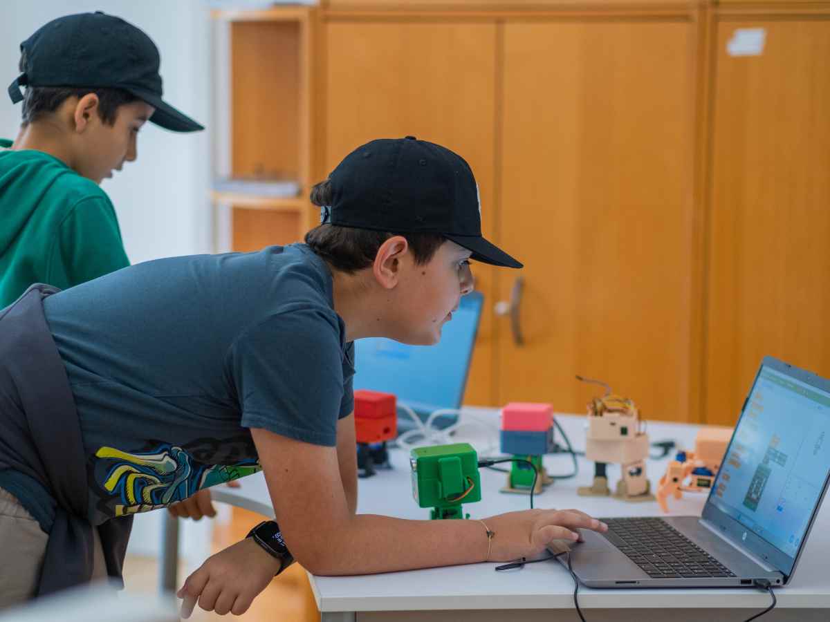 Kind programmiert am Laptop und arbeitet an Robotermodellen