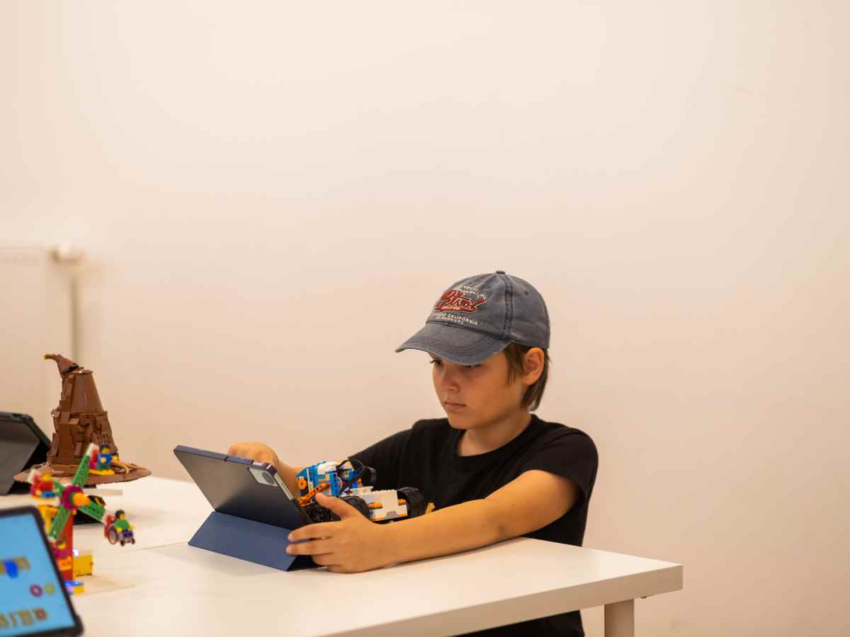 Kind arbeitet mit LEGO-Robotern und programmiert auf einem Tablet