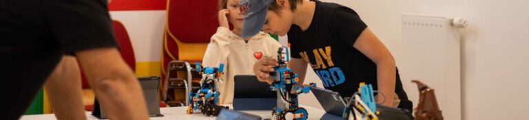 Zwei Kinder bauen und programmieren LEGO Roboter mit Tablet im ROBBO Club Wien