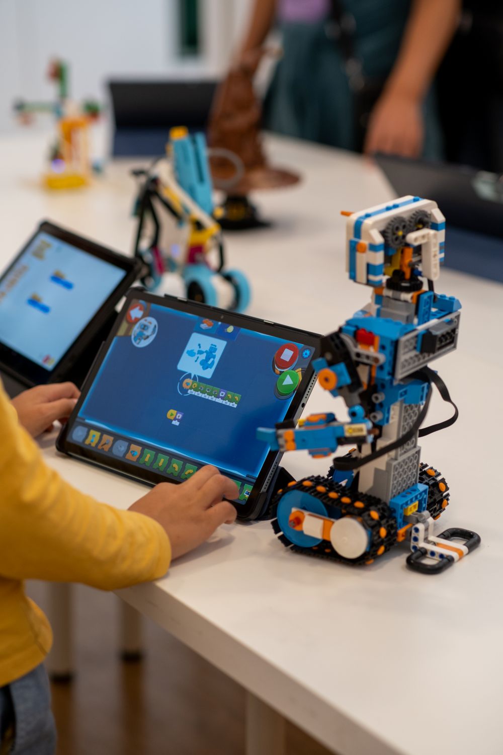 Kind programmiert Roboter mit Tablet beim Robbo Day