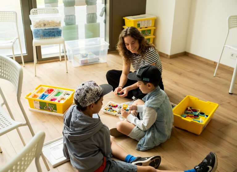 Eine Trainerin baut mit zwei Kindern am Boden mit LEGO Education SPIKE Essential im ROBBO Club 1030